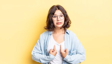 Genç ve güzel bir kız, şaşkın ve şaşkın bir bakışla kendini işaret ediyor. Seçildiğime şaşırmış ve şaşırmış.