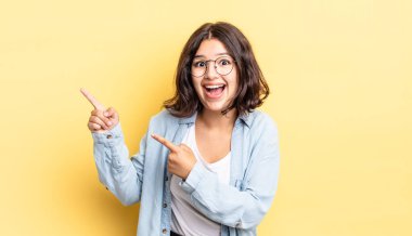 Genç, güzel bir kız kendini neşeli ve şaşırmış hissediyor. Şok olmuş bir ifadeyle gülümsüyor ve bir tarafı işaret ediyor.