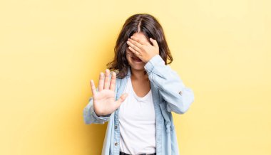 Genç ve güzel bir kız yüzünü eliyle kapatıyor ve kamerayı durdurmak için diğer elini öne koyuyor. Fotoğraf ya da resimleri reddediyor.