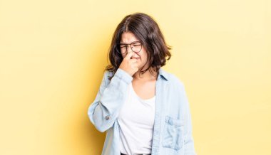 Genç güzel kız iğreniyor, kötü ve nahoş bir koku duymamak için burnunu tutuyor.