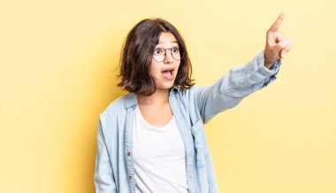 Genç, güzel bir kız şaşkın ve şaşırmış hissediyor. Şaşırmış ve ağzı açık bir şekilde hayranlıkla yukarı bakıyor.