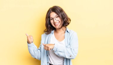 Genç ve güzel bir kız neşeyle gülümsüyor ve yan taraftaki fotokopi alanını gösteriyor, mutlu ve tatmin olmuş hissediyor.