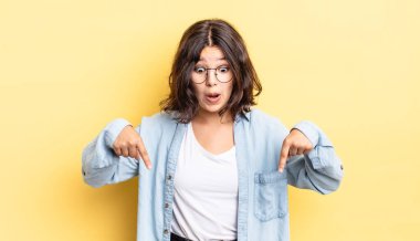 Genç, güzel bir kız şaşkın, ağzı açık ve şaşırmış, inançsızlık ve şaşkınlık içinde bakıyor ve onu işaret ediyor.