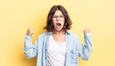 Genç ve güzel bir kız öfkeli bir ifadeyle ya da yumruklarıyla başarıyı kutlarken agresif bir şekilde bağırıyor.