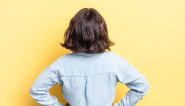 Genç, güzel bir kız, kafası karışık ya da dolu ya da şüphe ve soru dolu, merak ediyor, elleri kalçasında, dikiz aynasından.