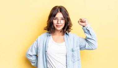 Genç güzel kız ciddi, güçlü ve isyankar hissediyor, yumruğunu kaldırıyor, protesto ediyor ya da devrim için savaşıyor.