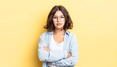 Genç, güzel bir kız hayal kırıklığına uğramış, hayal kırıklığına uğramış, ciddi görünüyor, kızgın ve kollarını kavuşturmuş.