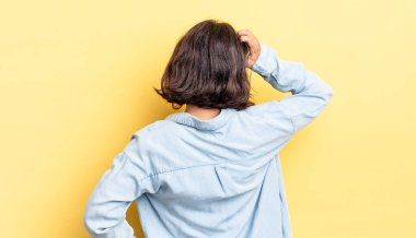 Genç, güzel bir kız bilgisiz ve kafası karışık, bir çözüm düşünüyor, eli kalçasında, diğeri kafasında, dikiz aynasından.