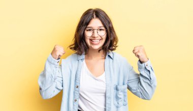 Genç güzel kız mutlu, pozitif ve başarılı hissediyor, zaferi, başarıları ya da iyi şansı kutluyor.