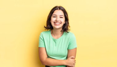 Genç ve güzel bir kız utangaç ve neşeli bir şekilde gülüyor, arkadaş canlısı ve olumlu ama güvensiz bir tavırla