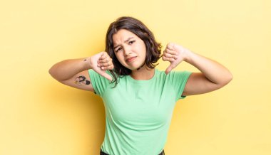 Genç, güzel bir kız üzgün, hayal kırıklığına uğramış ya da kızgın görünüyor, anlaşmazlık içinde başparmaklarını gösteriyor, hayal kırıklığına uğramış hissediyor.