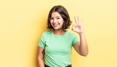 Genç güzel kız mutlu, rahat ve tatmin olmuş hissediyor. Onayını iyi bir hareketle gösteriyor. Gülümsüyor.