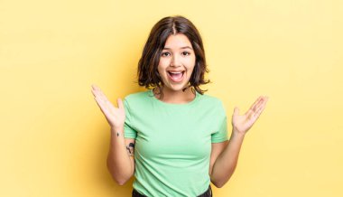 Genç güzel kız mutlu, heyecanlı, şaşırmış ya da şaşırmış hissediyor, gülümsüyor ve hayrete düşüyor.