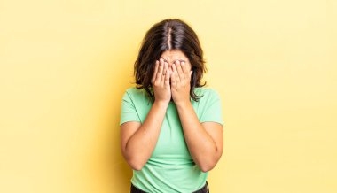 Genç, güzel bir kız üzgün, hayal kırıklığına uğramış, gergin ve depresif, iki eliyle yüzünü kaplayan, ağlayan