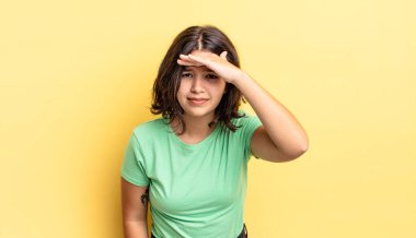 Genç ve güzel kız şaşkınlık ve şaşkınlık içinde bakıyor, el üstünde, uzaklara bakıyor, izliyor ya da arıyor.