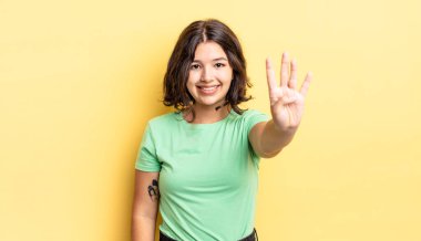 Genç, güzel bir kız gülümsüyor ve arkadaş canlısı görünüyor. Dört ya da dört numarayı gösteriyor. Elleri önde, geri sayıyor.