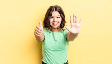 Genç ve güzel bir kız gülümsüyor ve arkadaş canlısı görünüyor, altı ya da altıncı numarayı gösteriyor, elleri önde, geriye doğru sayıyor.