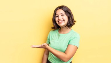 Genç ve güzel bir kız neşeyle gülümsüyor, mutlu hissediyor ve fotokopi alanında bir konsept gösteriyor.