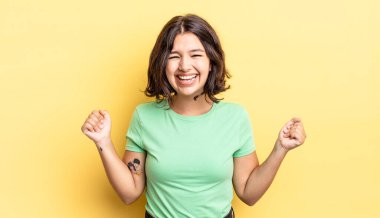 Genç ve güzel kız son derece mutlu ve şaşırmış görünüyor, başarıyı kutluyor, bağırıyor ve zıplıyor.