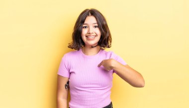 Genç güzel kız mutlu, gururlu ve şaşırmış görünüyor, neşeyle kendini gösteriyor, kendinden emin ve kibirli hissediyor.