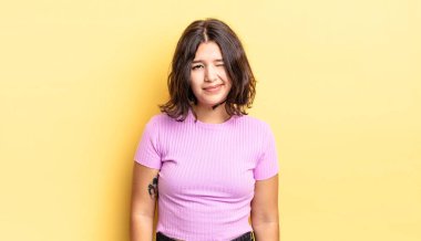 Genç ve güzel kız mutlu ve arkadaş canlısı görünüyor, gülümsüyor ve pozitif bir tavırla sana göz kırpıyor.