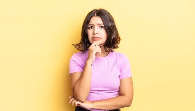 Genç ve güzel kız ciddi görünüyor, kafası karışık, kararsız ve düşünceli, seçenekler ve seçimler arasında şüpheci.