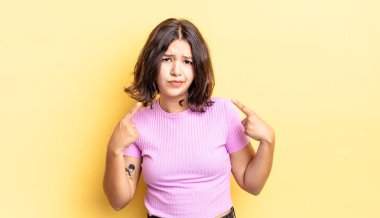 Kötü tavırlı genç ve güzel bir kız gururlu ve agresif görünüyor, yukarıyı işaret ediyor ya da elleriyle alay işareti yapıyor.