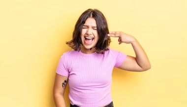 Genç ve güzel bir kız mutsuz ve stresli görünüyor, intihar jesti elle silah işareti yapıyor, kafasını işaret ediyor.