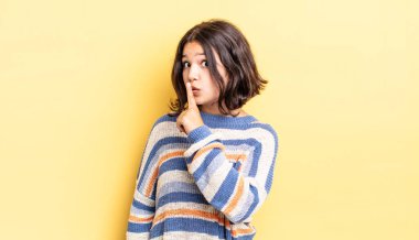 Genç ve güzel bir kız sessizlik ve sessizlik istiyor, parmaklarıyla ağzının önünde işaret ediyor, 