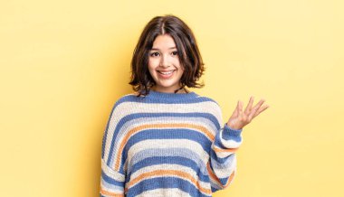 Genç, güzel bir kız mutlu, şaşırmış ve neşeli. Pozitif bir tavırla gülümsüyor. Bir çözüm ya da fikir buluyor.