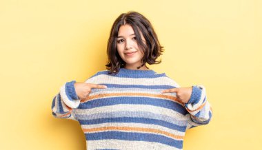 Genç ve güzel bir kız gururlu, pozitif ve iki eliyle göğsünü gösteren