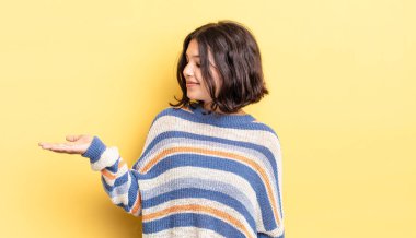 Genç, güzel bir kız kendini mutlu hissediyor ve gülümsüyor. Yanında duran bir nesneye ya da konsepte bakıyor.