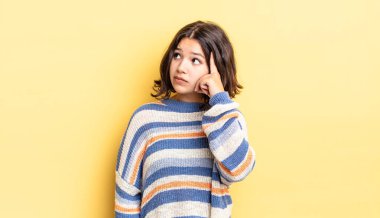 Yoğunlaşmış bakışları olan genç ve güzel bir kız şüpheli bir ifadeyle yukarı ve yana bakıyor.