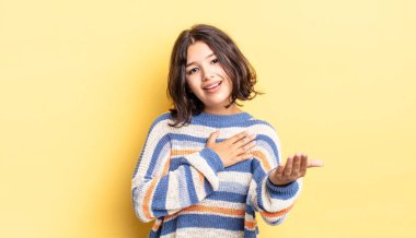 Genç ve güzel bir kız mutlu ve aşık, bir eli kalbinin yanında gülümsüyor ve diğer eli önde uzanıyor.