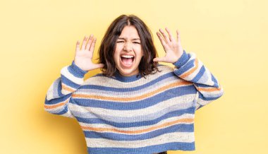 Genç ve güzel bir kız panik ya da öfke içinde bağırıyor, şok olmuş, korkmuş ya da öfkeli, elleri başının yanında.