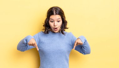 Genç, güzel bir kız şaşkın, ağzı açık ve şaşırmış, inançsızlık ve şaşkınlık içinde bakıyor ve onu işaret ediyor.