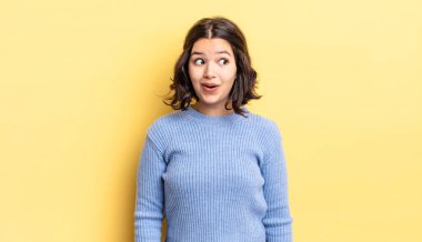 Genç, güzel bir kız şaşkın, mutlu, şaşkın ve şaşırmış hissediyor, ağzı açık bir şekilde yana bakıyor.