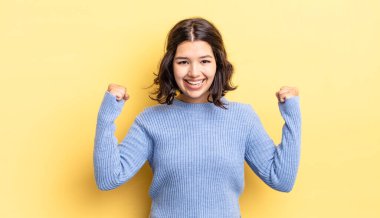 Genç güzel kız mutlu, pozitif ve başarılı hissediyor, zaferi, başarıları ya da iyi şansı kutluyor.