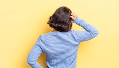 Genç, güzel bir kız bilgisiz ve kafası karışık, bir çözüm düşünüyor, eli kalçasında, diğeri kafasında, dikiz aynasından.