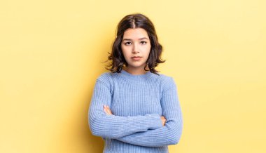 Genç, güzel bir kız hayal kırıklığına uğramış, hayal kırıklığına uğramış, ciddi görünüyor, kızgın ve kollarını kavuşturmuş.