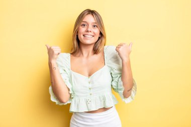 Sarışın, güzel bir kadın neşeyle gülümsüyor ve mutlu görünüyor, kaygısız ve pozitif hissediyor.