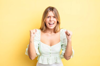 Sarışın, güzel bir kadın sinirli, sinirli, sinirli bakışlar ve sıkı yumruklar ile agresif bir şekilde bağırıyor.