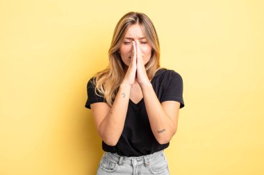 Sarışın, güzel bir kadın endişeli, umutlu ve dindar, sadık bir şekilde avuç içiyle dua ediyor, af diliyor.