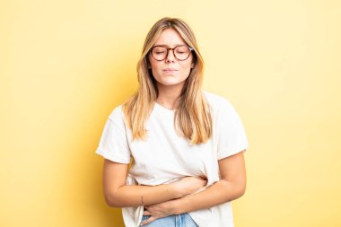 Sarışın, güzel bir kadın endişeli, hasta, hasta ve mutsuz hissediyor. Ağrılı bir mide ağrısı ya da grip geçiriyor.