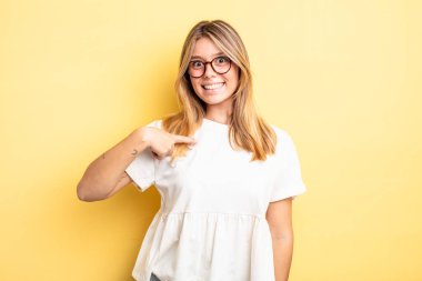 Sarışın, güzel bir kadın mutlu, gururlu ve şaşırmış görünüyor, neşeli bir şekilde kendini gösteriyor, kendinden emin ve kibirli hissediyor.