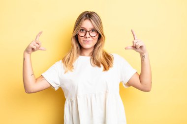 Sarışın, güzel bir kadın kendi gülüşünü çiziyor, iki eliyle, olumlu ve mutlu görünüyor, sağIık kavramı.