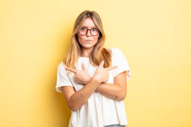 Şaşkın ve şaşkın görünen sarışın güzel kadın, güvensiz ve şüpheyle zıt yönleri işaret ediyor.