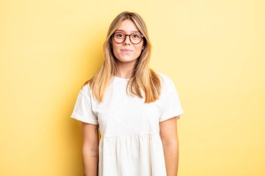 Sarışın, güzel bir kadın pozitif ve kendinden emin gülümsüyor. Tatmin olmuş, arkadaş canlısı ve mutlu görünüyor.