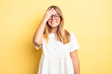 Sarışın, güzel bir kadın gülüyor ve alnına tokat atıyor. 