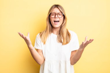 Sarışın, güzel bir kadın öfkeyle bağırıyor, stresli ve elleri havada neden ben diye bağırıyor.